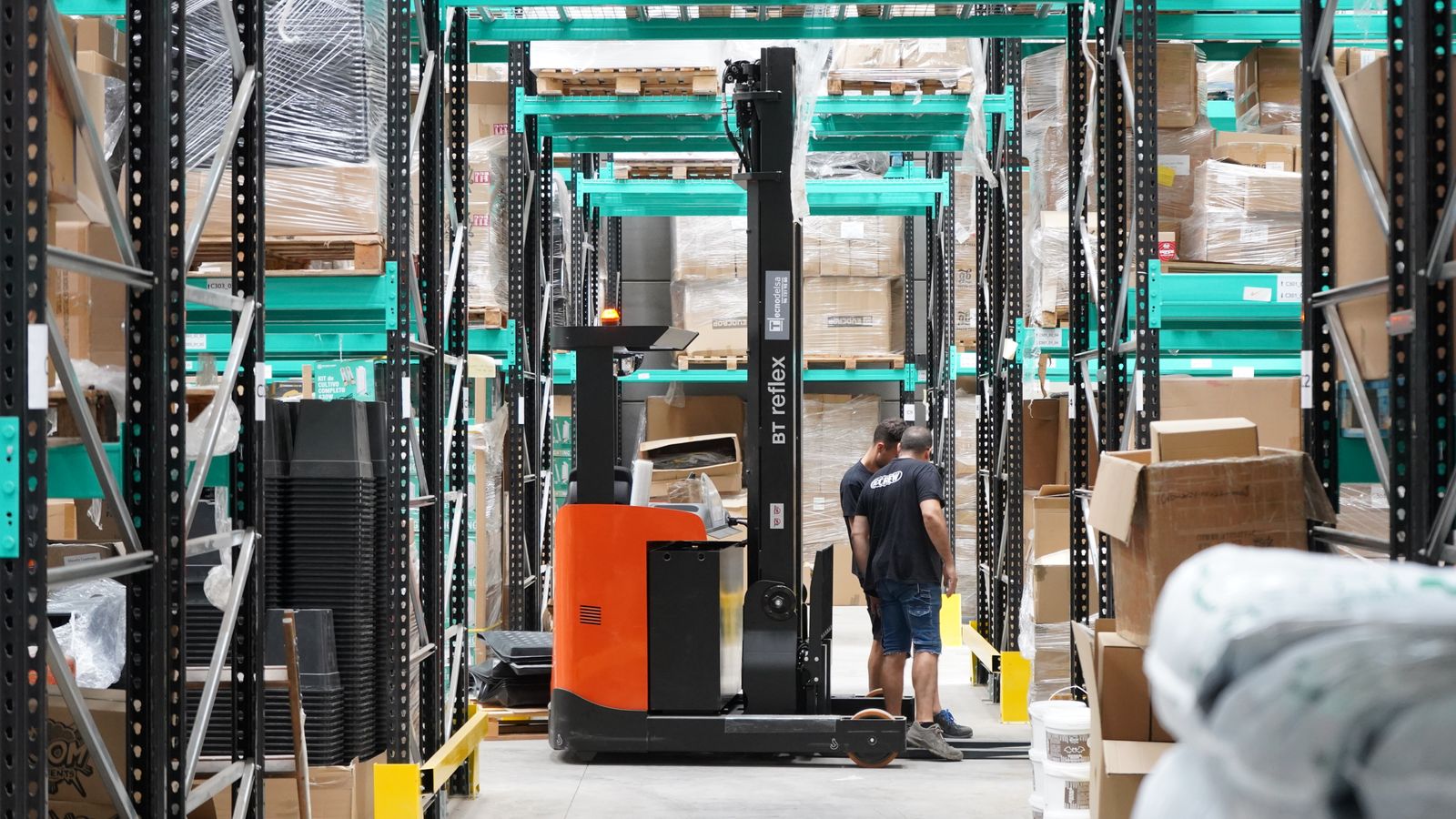Warehouse employee and reach truck among pallet storage racks